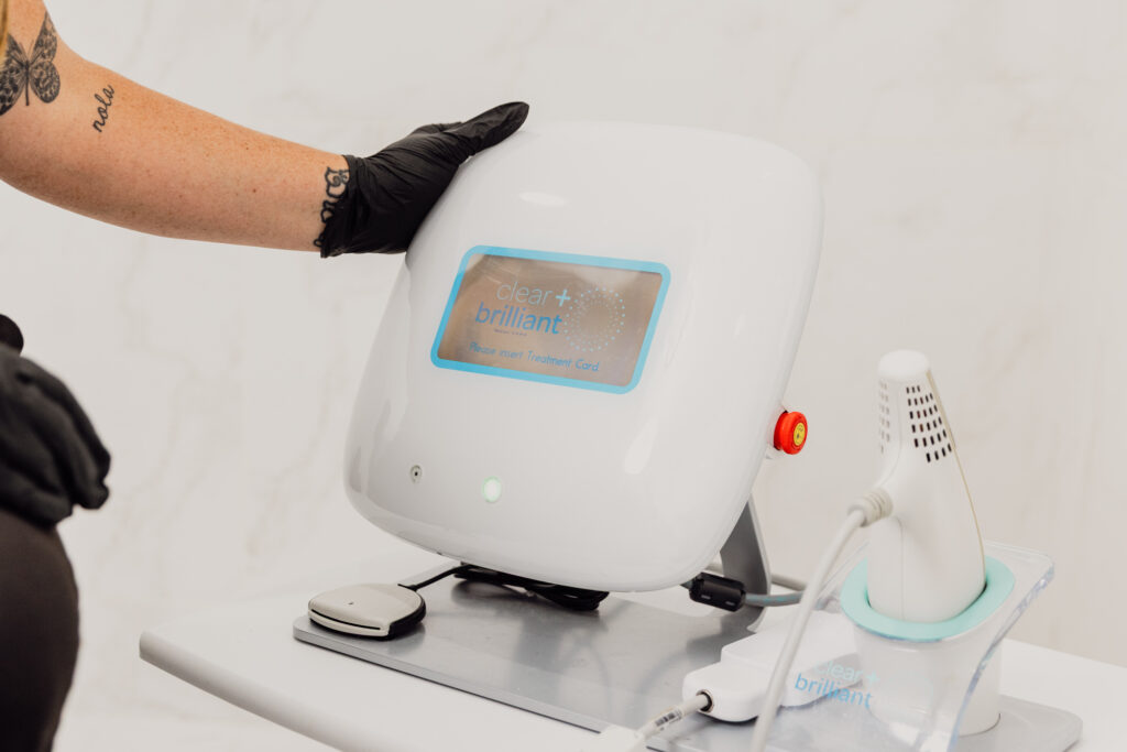 A provider's gloved hand reaches to touch the Clear + Brilliant device, our face rejuvenation laser treatment in St. Charles, IL, for promoting your skin's own healing power.