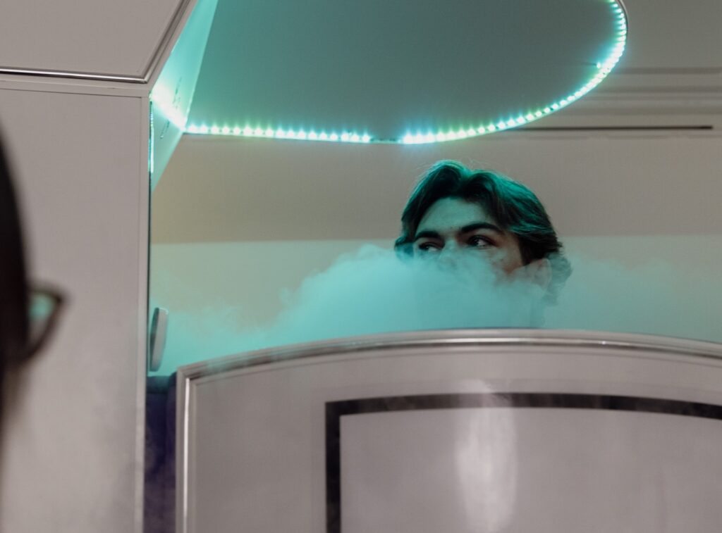 A male patient stands in the cryotherapy chamber, receiving invigorating treatment for anti-inflammatories in Tri-City, IL.